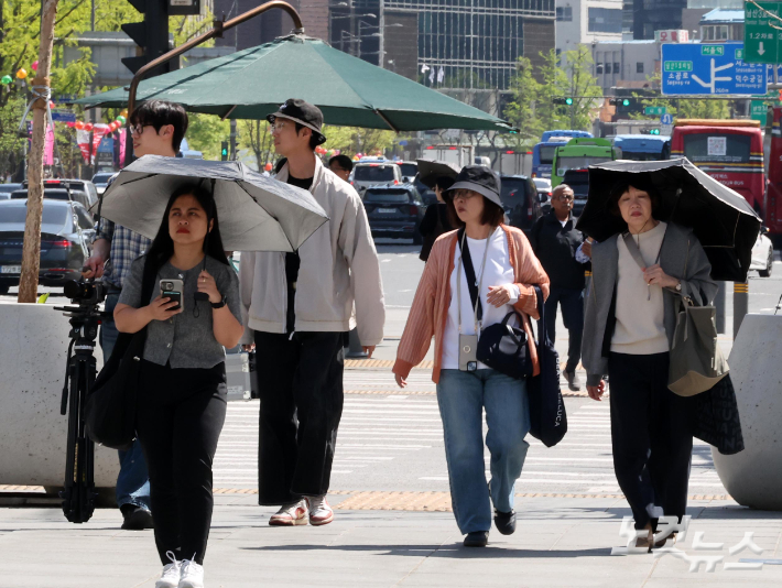 낮 최고기온이 28까지 오르는 등 초여름 날씨를 보인 16일 서울 광화문네거리에서 양산을 쓴 시민들이 발걸음을 옮기고 있다. 박종민 기자