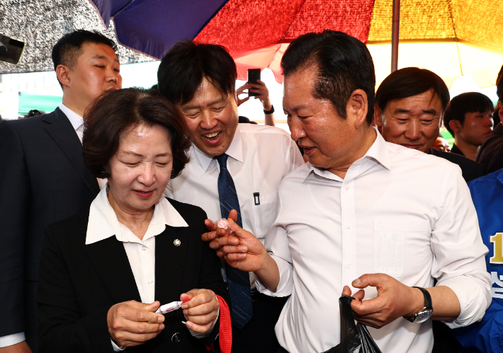 더불어민주당 정청래 대표가 19일 경기도 성남시 모란민속5일장을 방문해 김용 전 민주연구원 부원장에게 사탕을 건네고 있다. 연합뉴스