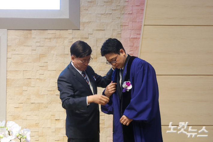 조대식 목사가 최부성 목사에게 목회 가운을 전달하며 담임목사직을 위임하고 있다. 최화랑 기자