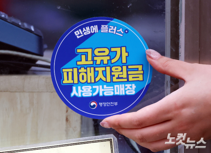 고유가 피해지원금 1차 지급이 시작된 27일 서울 강서구 남부골목시장에서 상인들이 '고유가 피해지원금 사용가능매장' 스티커를 부착하고 있다. 황진환 기자