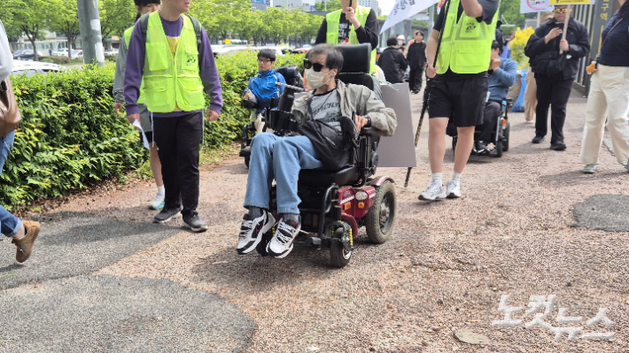 29일 오전 10시 40분쯤 광주 서구 유스퀘어 터미널 앞에서 장애인단체 회원이 휠체어를 타고 행진하고 있다. 울퉁불퉁하게 파손된 인도 위에서 휠체어가 휘청거리고 있다. 한아름 기자