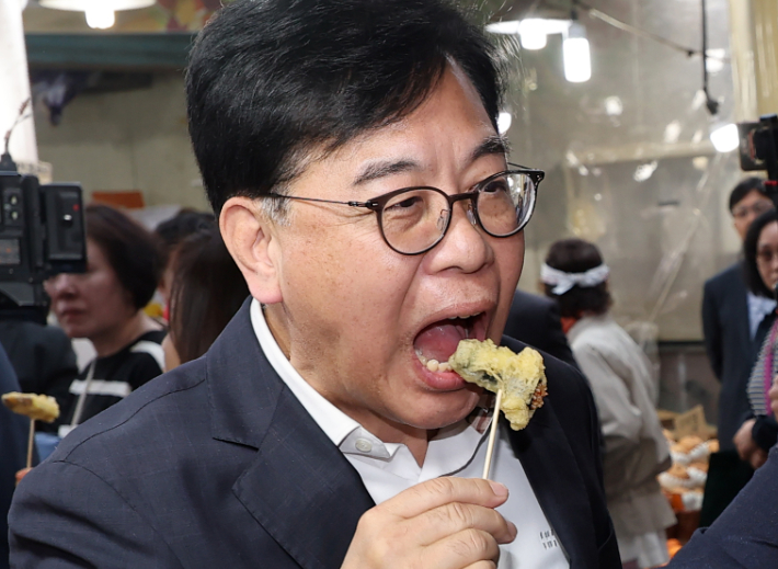 국민의힘 송언석 원내대표가 4일 서울 강서구 화곡본동시장을 방문, 한 상점에서 튀김을 맛보고 있다. 연합뉴스