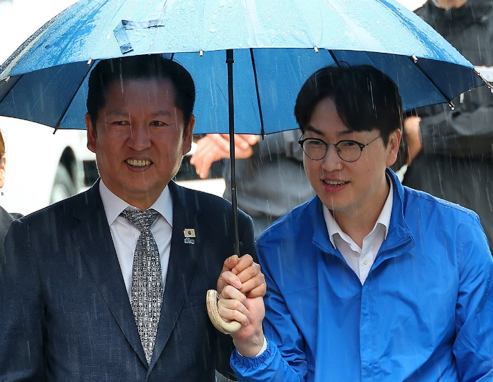 3일 오후 부산 북구 구포시장에서 더불어민주당 정청래 대표와 북갑 국회의원 보궐선거 출마를 공식화한 하정우 전 청와대 AI 미래기획수석이 우산을 쓰고 이동하고 있다. 연합뉴스