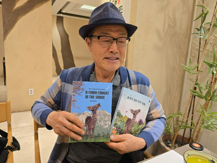 오문수 저자가 '올무에 걸린 아기사슴' 한영 소설을 함께 들고 있다. 독자 제공