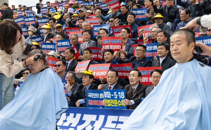 지난 4월 23일 국회 본청 앞에서 시민주도 헌법개정 전국 네트워크가 주최한 부마항쟁 및 5·18 정신 헌법전문 수록 촉구 대회에서 참가자들이 헌법 개정을 촉구하며 삭발하는 부마항쟁과 5.18 민주화 운동 단체 대표자들을 바로보며 구호를 외치고 있다. 연합뉴스