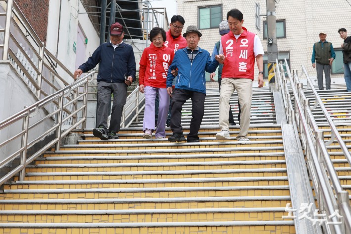 오세훈 국민의힘 서울시장 후보가 11일 오후 서울 구로구 고척동 주택가를 방문해 고지대 이동약자 편의시설 관련 브리핑을 받은 후 어르신들과 계단을 내려오고 있다.