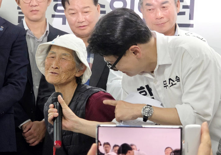 무소속 한동훈 부산 북갑 국회의원 보궐선거 후보가 10일 부산 북구에서 열린 선거사무소 개소식에서 '토마토, 찰밥 할매' 김복악씨를 소개하고 있다. 좌판에서 채소를 파는 김 할머니는 얼마 전 한 후보에게 토마토를 건넸고, 한 후보를 주기 위해 찰밥을 지어 한 후보에게 건네 화제가 됐다. 연합뉴스