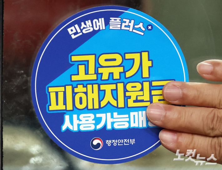 윤호중 행정안전부 장관이 고유가 피해지원금 1차 지급이 시작된 27일 서울 강서구 남부골목시장을 찾아 상인들과 함께 '고유가 피해지원금 사용가능매장' 스티커를 부착하고 있다. 황진환 기자
