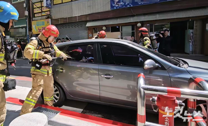 13일 부산 부산진구 한 도로에서 소방대원들이 소화전 앞 불법 주차 차량을 가정한 승용차 창문을 부수고 있다. 박진홍 기자