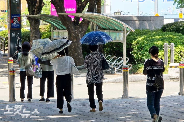 부산의 한 거리에서 시민들이 양산을 쓰고 걷고 있다. 송호재 기자