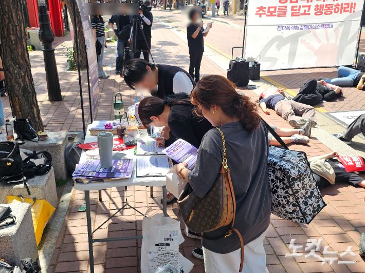 서울 혜화역 소나무길을 지나가던 시민들이 서명에 동참하고 있다. 나채영 기자