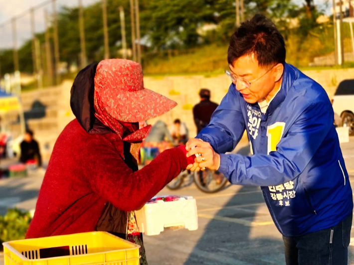 상인과 악수를 나누고 있는 더불어민주당 김중남 강릉시장 예비후보. 김 후보 페이스북 캡처