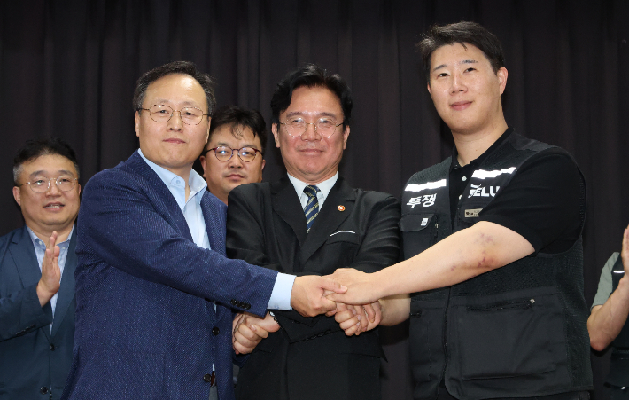 20일 경기도 수원시 장안구 경기고용노동청에서 열린 삼성전자 임금협상을 마친 후 여명구 삼성전자 DS(디바이스솔루션·반도체 사업 담당) 피플팀장과 최승호 삼성그룹 초기업노동조합 삼성전자지부 위원장이 잠정 합의안에 서명한 후 김영환 고용노동부 장관과 손을 맞잡고 있다. 연합뉴스