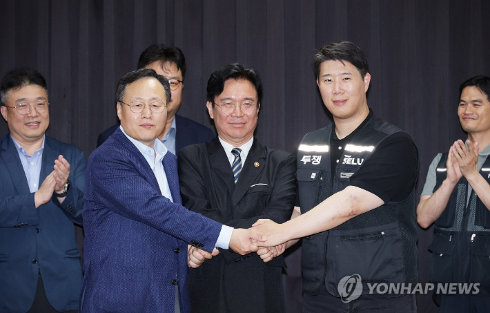 (수원=연합뉴스) 홍기원 기자 = 20일 경기도 수원시 장안구 경기고용노동청에서 열린 삼성전자 임금협상을 마친 후 여명구 삼성전자 DS(디바이스솔루션·반도체 사업 담당) 피플팀장과 최승호 삼성그룹 초기업노동조합 삼성전자지부 위원장이 잠정 합의안에 서명한 후 김영훈 고용노동부 장관과 손을 맞잡고 있다. 2026.5.20 [공동취재] xanadu@yna.co.kr 연합뉴스
