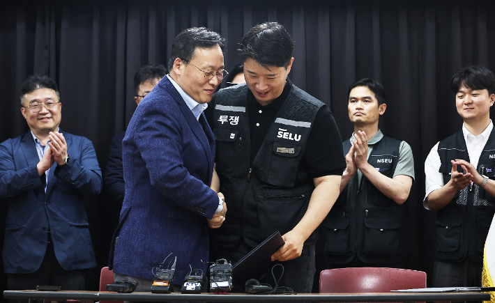 20일 경기도 수원시 장안구 경기고용노동청에서 열린 삼성전자 임금협상을 마친 후 여명구 삼성전자 DS(디바이스솔루션·반도체 사업 담당) 피플팀장과 최승호 삼성그룹 초기업노동조합 삼성전자지부 위원장이 잠정 합의안에 서명한 후 손을 맞잡고 있다. 연합뉴스