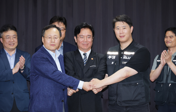 지난 20일 경기도 수원시 장안구 경기고용노동청에서 열린 삼성전자 임금협상을 마친 후 여명구 삼성전자 DS(디바이스솔루션·반도체 사업 담당) 피플팀장과 최승호 삼성그룹 초기업노동조합 삼성전자지부 위원장이 잠정 합의안에 서명한 후 김영환 고용노동부 장관과 손을 맞잡고 있다. 연합뉴스
