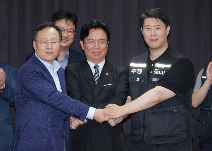 여명구 삼성전자 DS(디바이스솔루션·반도체 사업 담당) 피플팀장과 최승호 삼성그룹 초기업노동조합 삼성전자지부 위원장이 잠정 합의안에 서명한 후 김영환 고용노동부 장관과 손을 맞잡고 있다. 연합뉴스
