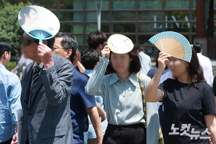 서울 광화문네거리에서 시민들이 부채로 햇볕을 가리고 있다. 류영주 기자