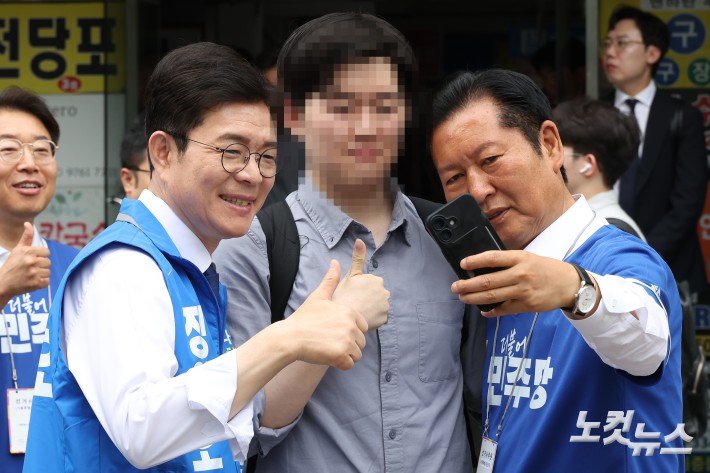 정청래 더불어민주당 대표와 정원오 서울시장 후보가 26일 서울 영등포구 여의도역 5번 출구 앞에서 출근길 인사를 하며 시민과 셀카를 찍고 있다.