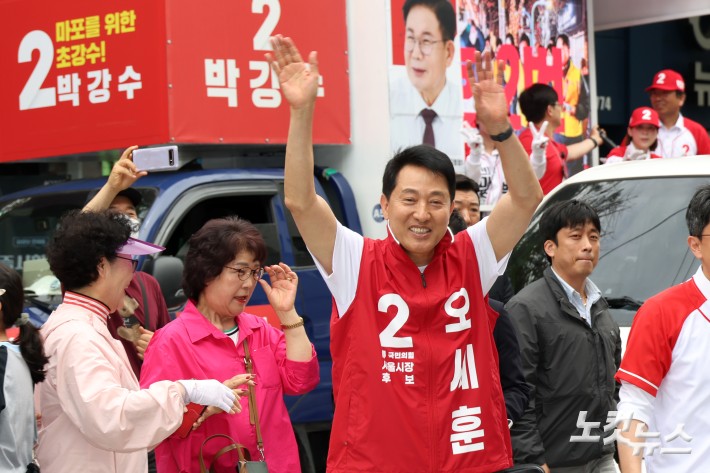 오세훈 국민의힘 서울시장 후보가 26일 서울 마포구 망원시장을 순회하며 유권자들을 향해 손을 들어 인사를 하고 있다.