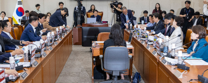26일 국회에서 열린 행정안전위원회 전체 회의에서 더불어민주당 의원들과 국민의힘 의원들이 정원오ㆍ오세훈 서울시장 후보 비판이 적힌 종이를 상임위 노트북에 붙인 이후 여야 간사단 합의를 통해 다시 떼고 있다. 연합뉴스