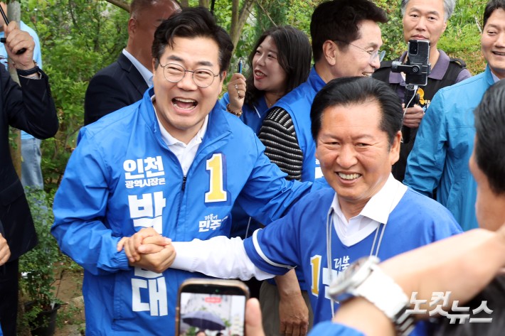 더불어민주당 정청래 대표와 박찬대 인천시장 후보가 27일 인천시 강화군 강화풍물시장 총집중유세에서 만나 손을 잡고 인사를 하고 있다.