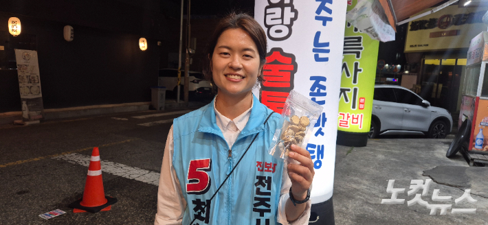 26일 저녁 상가방문 중 상인이 "힘내라"며 준 뻥튀기 봉지를 들고 웃는 최한별 진보당 전주시의원(전주시카) 후보. 심동훈 기자