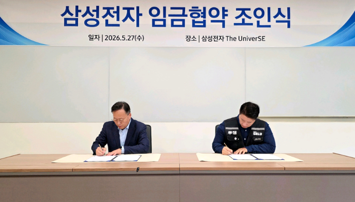 삼성전자 여명구 부사장(왼쪽)과 삼성그룹 초기업노동조합 삼성전자 지부 최승호 위원장이 지난 27일 경기 용인시 기흥에 위치한 삼성전자 The UniverSE에서 열린 2026년 임금협약 조인식에서 서명하는 모습. 연합뉴스