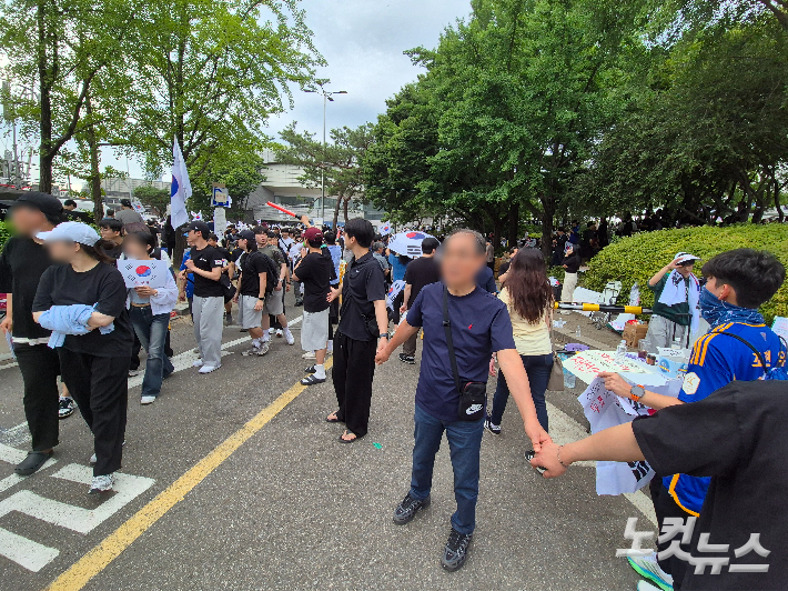 7일 오후 서울 송파구 올림픽공원 핸드볼경기장 앞 집회에서 일부 참가자들이 자원해 양쪽으로 손을 잡고 벌려 인간 띠를 만들고 통행로를 확보하고 있다. 송선교 기자