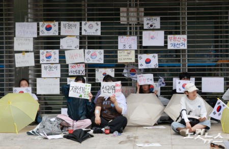 6·3 지방선거 투표용지 부족 사태를 규탄하고 재선거를 요구하는 '잠실 개표소 봉쇄 시위'가 나흘째 이어지고 있는 8일 서울 송파구 올림픽공원 핸드볼경기장 출입구 앞에서 시위 참가자들이 구호를 외치고 있다.