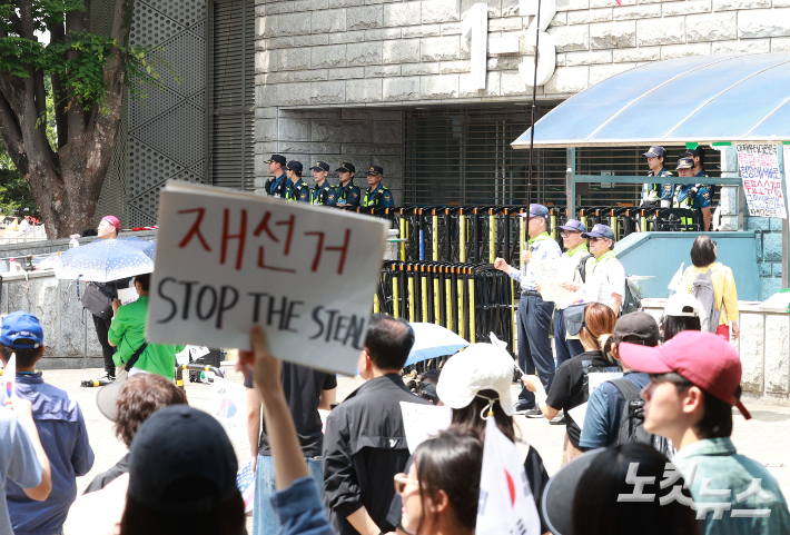 6·3 지방선거 투표용지 부족 사태를 규탄하고 재선거를 요구하는 '잠실 개표소 봉쇄 시위'가 나흘째 이어지고 있는 8일 서울 송파구 올림픽공원 핸드볼경기장 출입구 앞에서 시위 참가자들이 구호를 외치고 있다. 류영주 기자