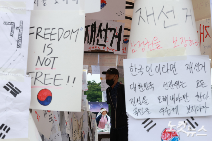 6·3 지방선거 투표용지 부족 사태를 규탄하고 재선거를 요구하는 '잠실 개표소 봉쇄 시위'가 나흘째 이어지고 있는 8일 서울 송파구 올림픽공원 핸드볼경기장 인근 티켓박스에 재선거를 요구하는 종이들이 붙어 있다. 류영주 기자