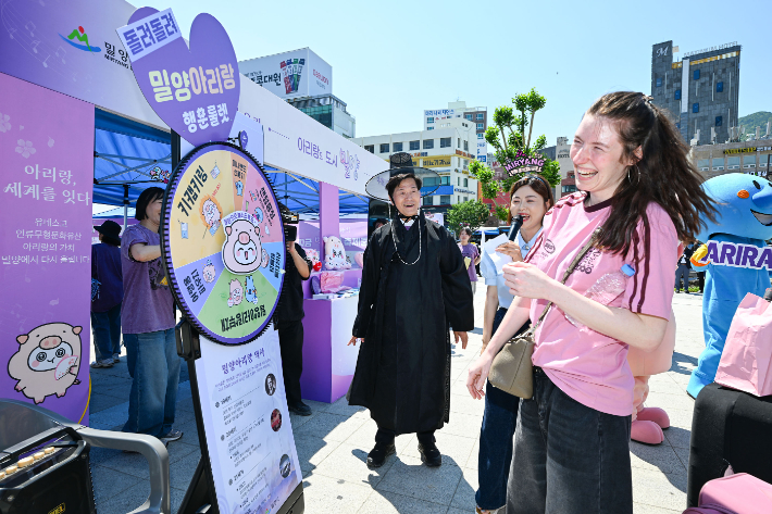 12~13일 부산역 광장에서 운영된 '2026 밀양 브랜드로드쇼' 홍보부스에서 관광객들이 밀양아리랑 행운의 룰렛 이벤트에 참여하며 즐거운 시간을 보내고 있다. 밀양시 제공
