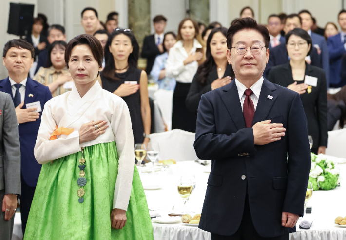 이재명 대통령과 김혜경 여사가 15일(현지시간) 로마 한 호텔에서 열린 동포 오찬 간담회에서 국기에 경례하고 있다. 연합뉴스