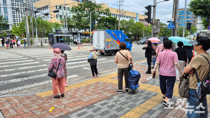18일 대구 서구의 한 횡단보도에서 시민들이 양산과 모자로 햇볓을 피하고 있다. 정진원 기자