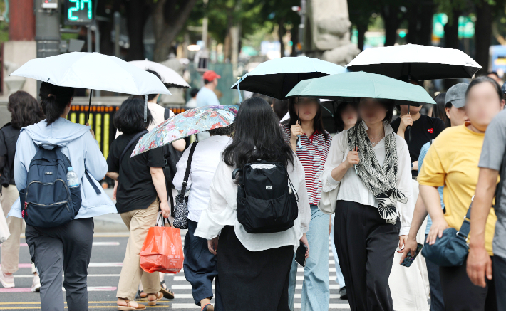 서울에 올여름 첫 폭염주의보가 발령됐다. 18일 서울 광화문광장 인근 횡단보도에서 양산을 쓴 시민들이 길을 건너고 있다. 연합뉴스