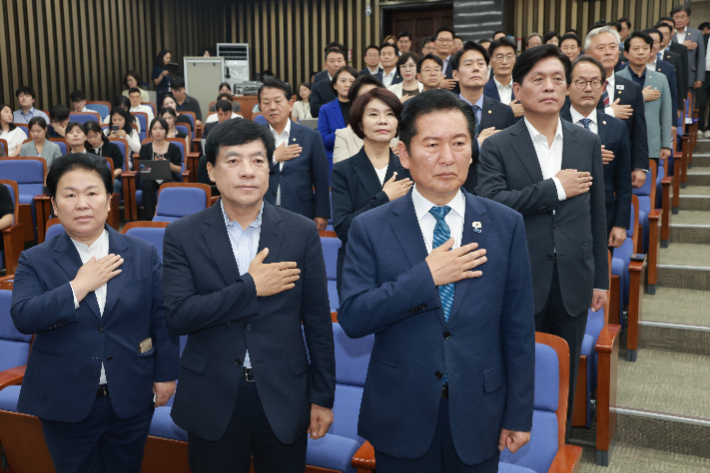 더불어민주당 정청래 대표와 의원들이 18일 국회에서 본회의를 앞두고 열린 의원총회에 참석해 국기에 경례하고 있다. 연합뉴스