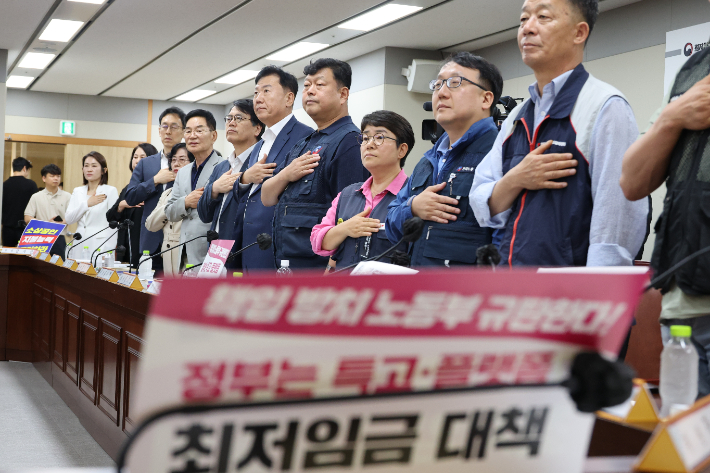 지난 18일 정부세종청사 최저임금위원회에서 열린 제7차 전원회의에서 근로자·사용자·공익 위원들이 국기에 경례하고 있다. 연합뉴스
