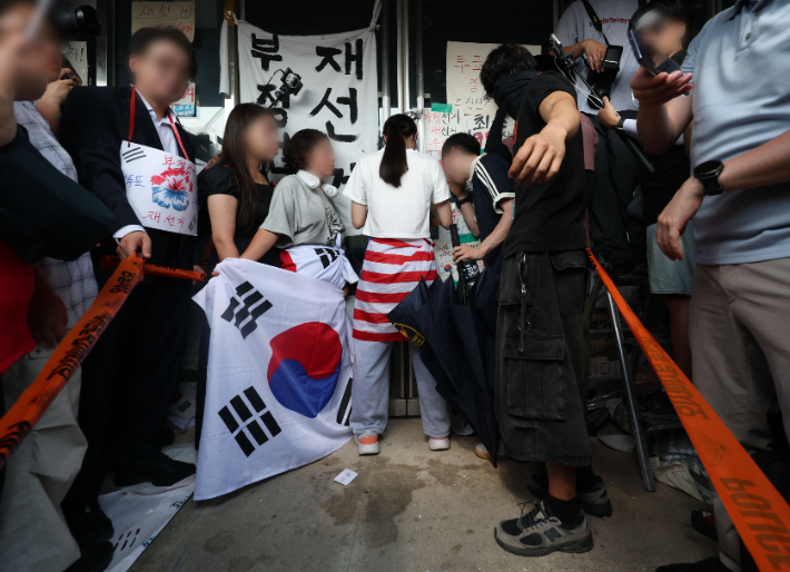 6·3 지방선거 투표용지 부족 사태로 시작한 서울 송파구 올림픽공원 핸드볼경기장 일대 '개표소 봉쇄 시위'가 이어진 16일 한 시위 참가자가 문을 가로막아 체육단체 직원들이 경기장 안으로 들어가지 못하고 있다. 연합뉴스