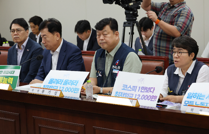 23일 정부세종청사 최저임금위원회에서 열린 제8차 전원회의에서 근로자위원인 이미선 민주노총 부위원장이 "코스피 1만보다 최저임금 1만2천원!" 이라고 적은 피켓을 세워두고서 발언하고 있다. 연합뉴스