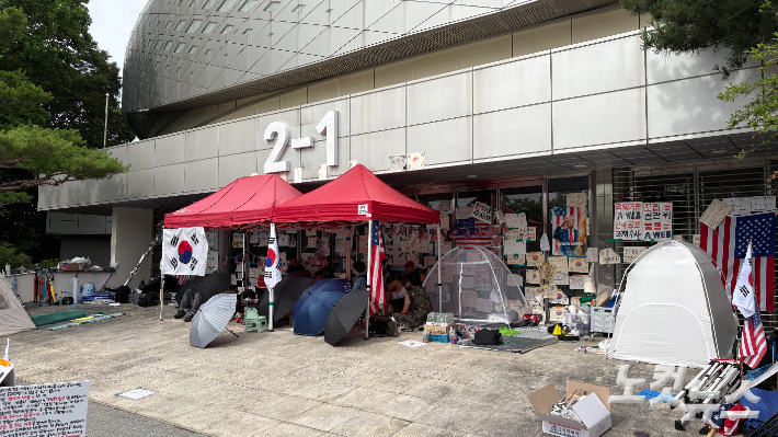24일 오후 서울 송파구 올림픽공원 핸드볼경기장 입구 앞에 텐트와 모기장 등이 설치돼 시위 참가자들이 앉아 있다. 김수정 기자