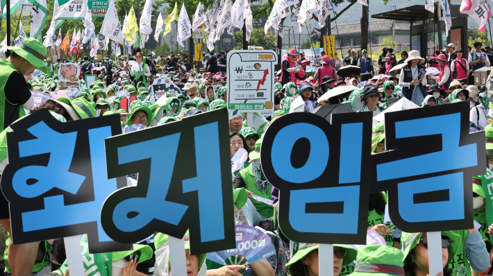 27일 서울 종로구 열린송현녹지광장 앞에서 열린 민주노총 최저임금 인상 결의대회에서 참석자들이 손피켓을 들고 있다. 연합뉴스