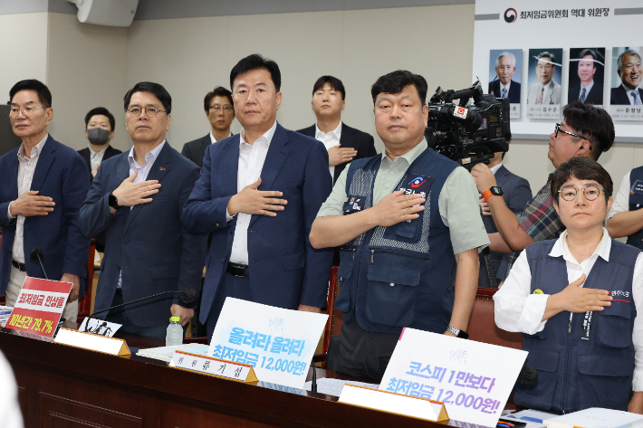 23일 정부세종청사 최저임금위원회에서 열린 제8차 전원회의에서 사용자위원과 근로자위원들이 국기에 경례하고 있다. 연합뉴스