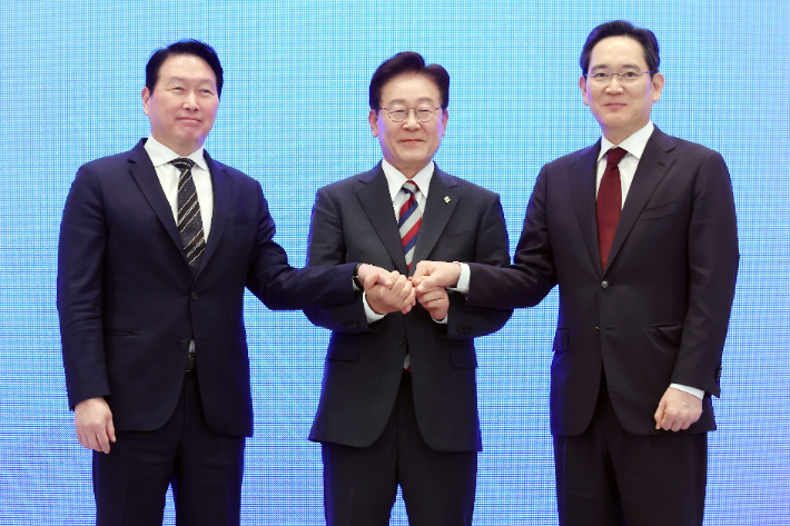  이재명 대통령과 이재용 삼성전자 회장, 최태원 SK그룹 회장이 29일 청와대에서 열린 3대 메가프로젝트 국민보고회에서 기업 투자계획 발표 후 손을 잡고 있다. 연합뉴스