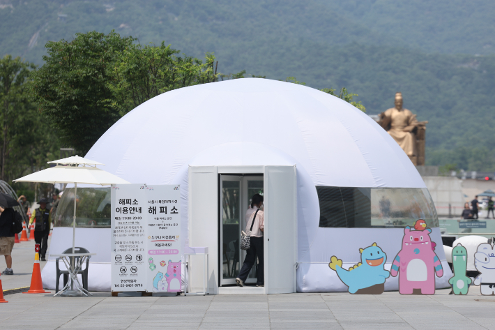 무더운 날씨가 이어진 29일 서울 광화문광장에 설치된 서울시 폭염대피시설 '해피소'에서 시민들이 더위를 식히고 있다.  연합뉴스