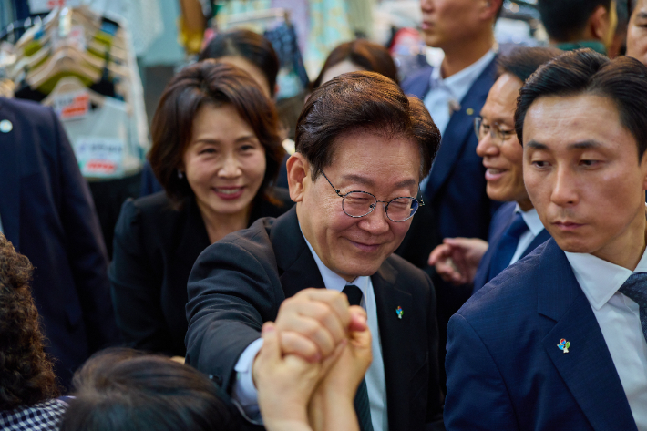 이재명 대통령과 김혜경 여사가 25일 수원 팔달문시장에서 상인들과 인사하고 있다. 청와대 제공
