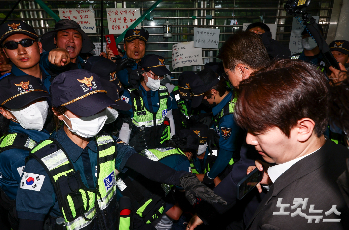 6·3 지방선거 투표용지 부족 사태를 조사 중인 국회 국정조사특별위원회 위원들이 지난 2일 서울 송파구 올림픽공원 내 개표소를 찾은 가운데 출입문을 가로막은 시위 참가자가 경찰에 연행되는 모습. 국회사진기자단