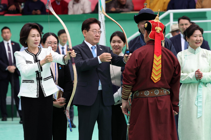 몽골을 국빈방문 중인 이재명 대통령과 김혜경 여사가 11일(현지시간) 나담축제가 열리고 있는 울란바타르 전통 활쏘기 경기장에서 활 쏘는 법을 배우고 있다. 연합뉴스