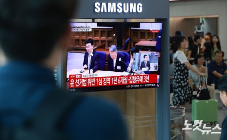 27일 서울 용산구 서울역 대합실에서 시민들이 윤석열 전 대통령의 공직선거법 위반 혐의 1심 선고 생중계를 보고 있다. 이날 법원은 윤석열에게 징역 1년 6개월에 집행유예 3년을 선고했다.