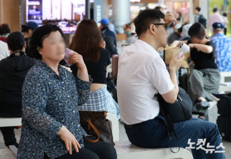 27일 서울 용산구 서울역 대합실에서 열차를 기다리는 시민들이 손수건과 손선풍기로 더위를 식히고 있다. 이날 행정안전부는 오후 3시부로 폭염 재난 위기경보를 